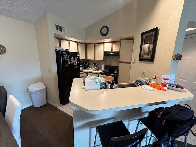 kitchen with visible vents, light countertops, vaulted ceiling, a peninsula, and black appliances