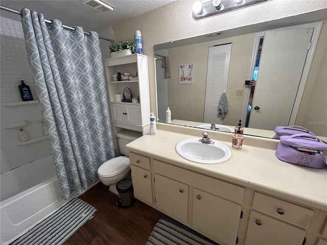 bathroom with visible vents, toilet, wood finished floors, vanity, and a textured wall