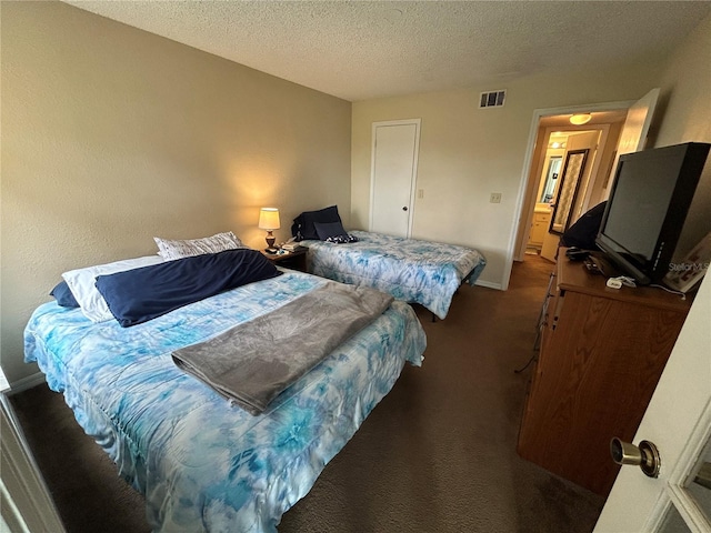 bedroom featuring visible vents, dark carpet, a textured ceiling, and baseboards