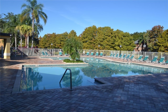 pool with a patio area and fence