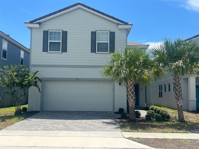 traditional home featuring decorative driveway, an attached garage, and stucco siding