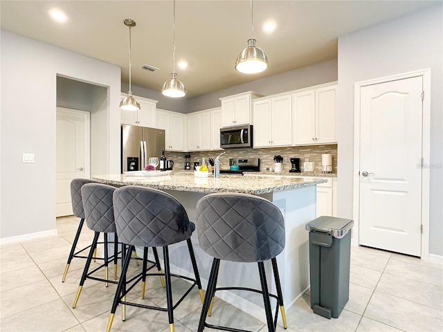 kitchen with tasteful backsplash, appliances with stainless steel finishes, visible vents, and a kitchen breakfast bar