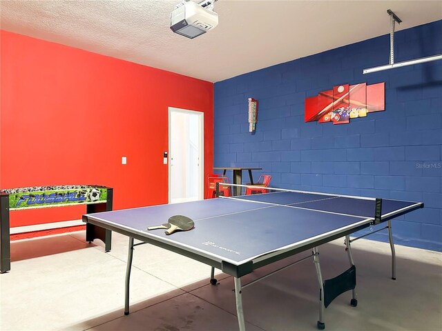 game room with a textured ceiling and concrete flooring