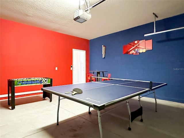 recreation room featuring a textured ceiling and a garage