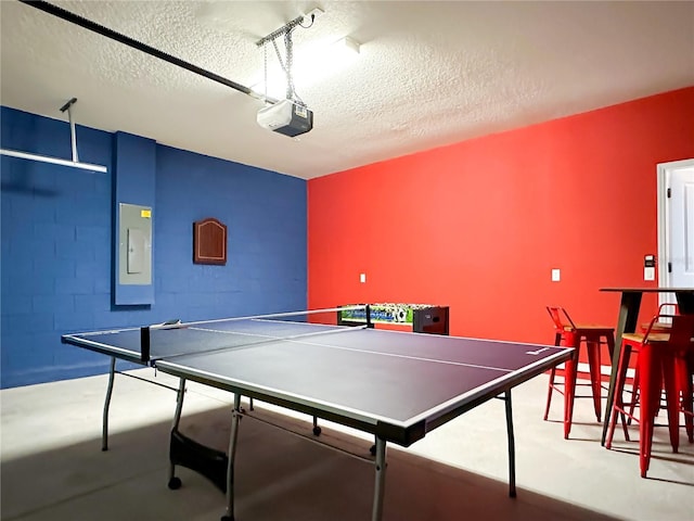 rec room featuring a garage, electric panel, and a textured ceiling