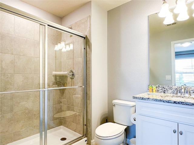 bathroom featuring toilet, a stall shower, visible vents, and vanity