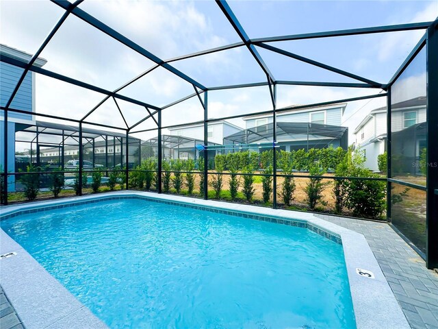 view of swimming pool featuring glass enclosure