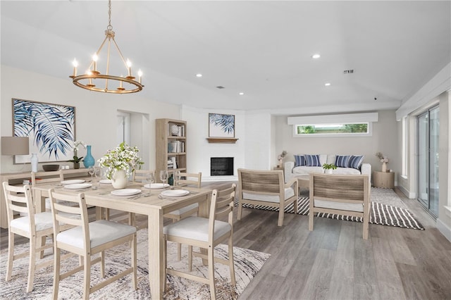 dining space featuring a fireplace, hardwood / wood-style floors, and a notable chandelier