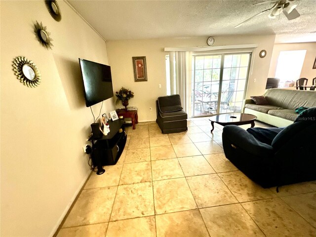 living room with ceiling fan, baseboards, light tile patterned flooring, and a textured ceiling