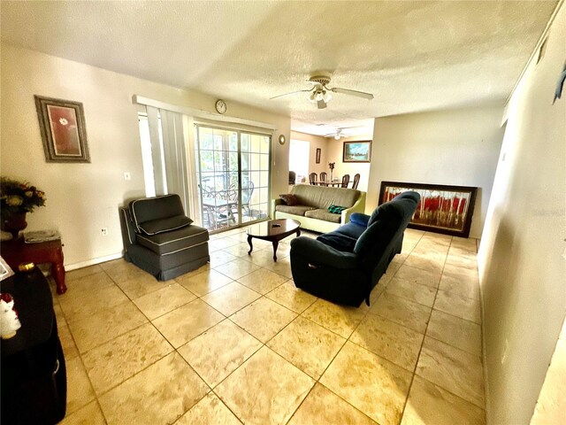 living area with a ceiling fan, a textured ceiling, and light tile patterned flooring