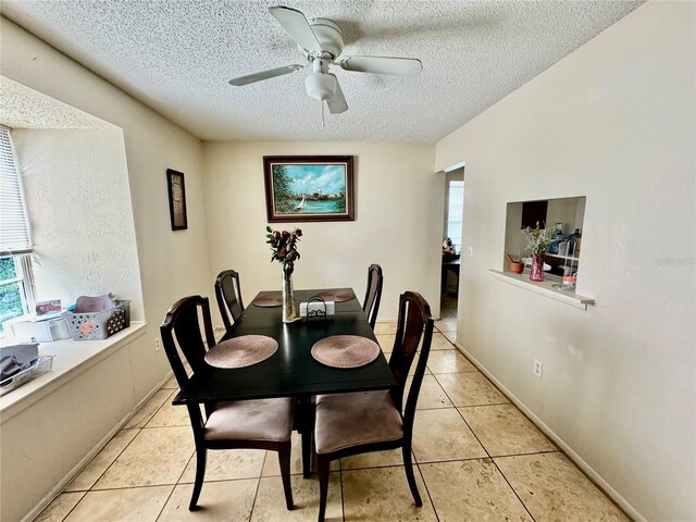 dining room featuring ceiling fan, a healthy amount of sunlight, a textured ceiling, and light tile patterned flooring