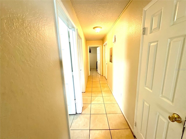 hallway with a textured ceiling and light tile patterned floors