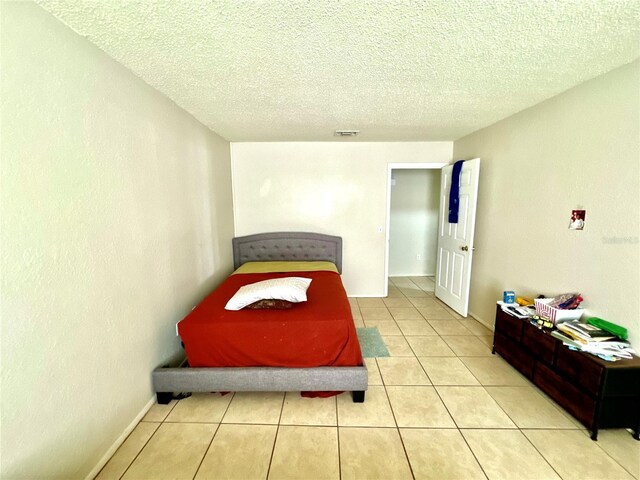 tiled bedroom with a textured ceiling and visible vents