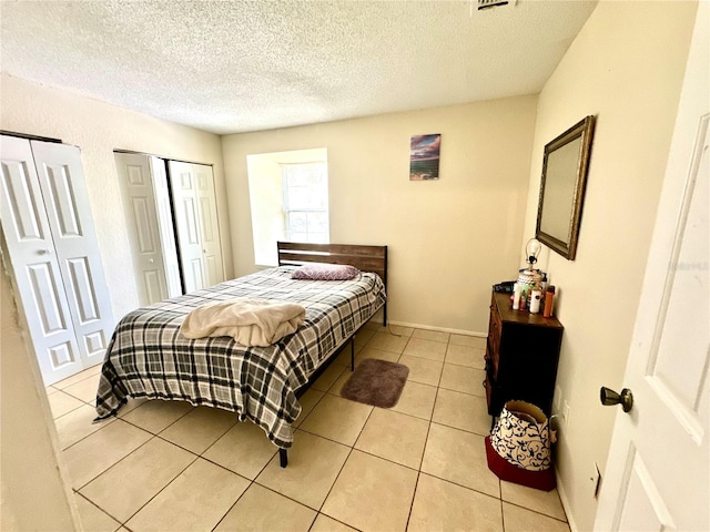 tiled bedroom featuring a textured ceiling and multiple closets