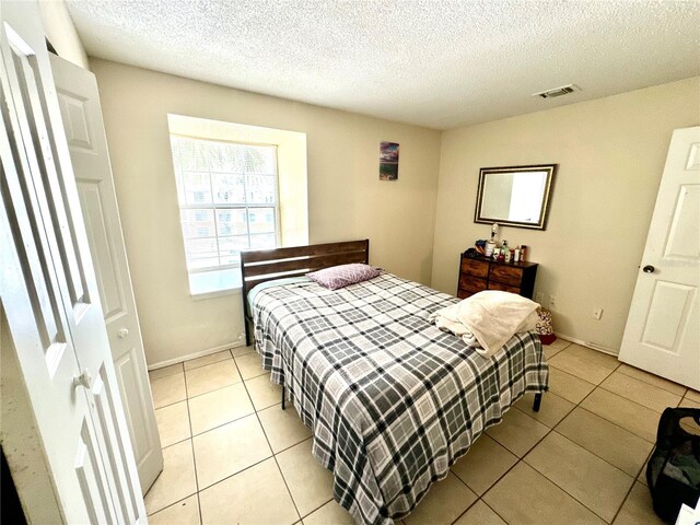 bedroom featuring a textured ceiling, visible vents, and light tile patterned floors