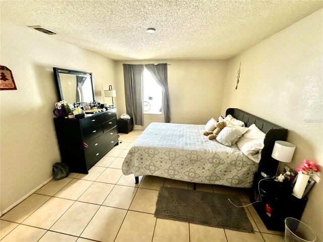 bedroom with visible vents, a textured ceiling, and light tile patterned flooring