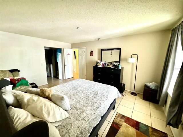 bedroom with visible vents, a textured ceiling, and light tile patterned floors