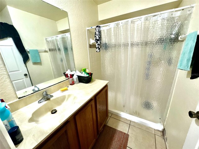 bathroom featuring vanity, a textured wall, tile patterned flooring, and a shower with shower curtain