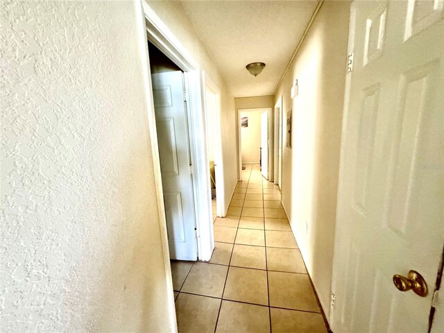 hall with a textured wall and light tile patterned flooring
