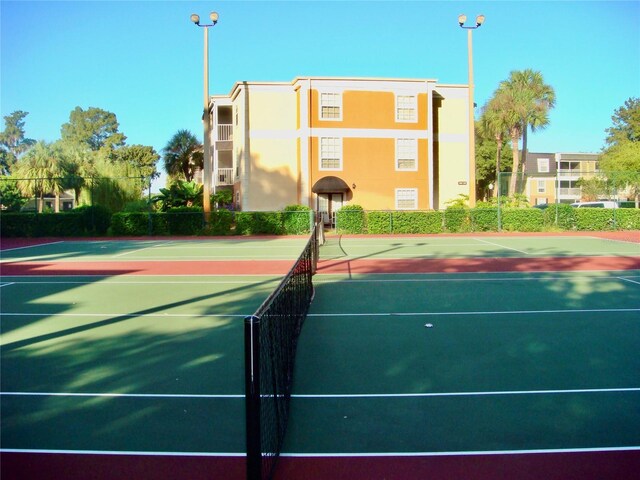 view of tennis court with community basketball court and fence