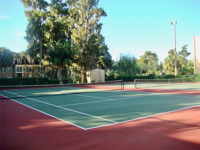 view of tennis court featuring community basketball court and fence