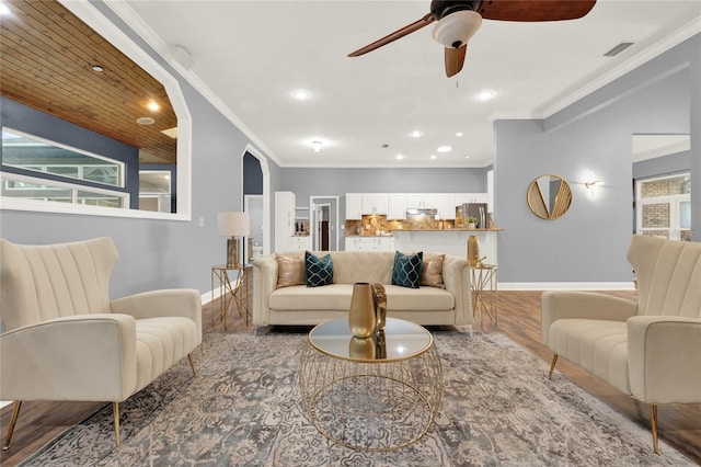 living room with ornamental molding, wood-type flooring, and ceiling fan