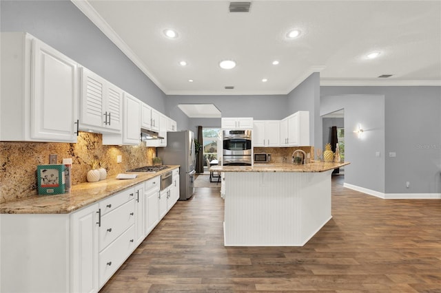 kitchen featuring stainless steel appliances, white cabinetry, light stone counters, and a kitchen bar