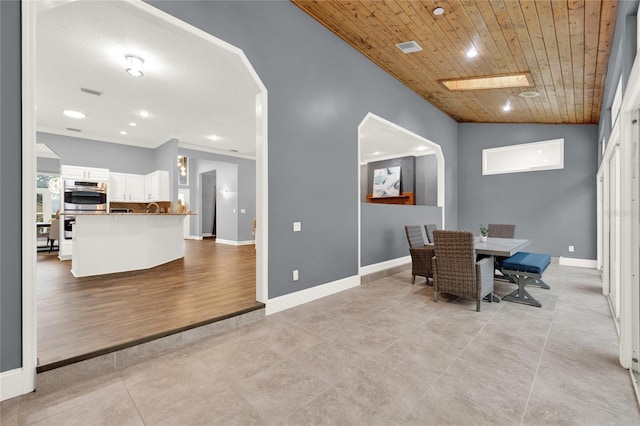 tiled dining space with ornamental molding, vaulted ceiling, and wooden ceiling