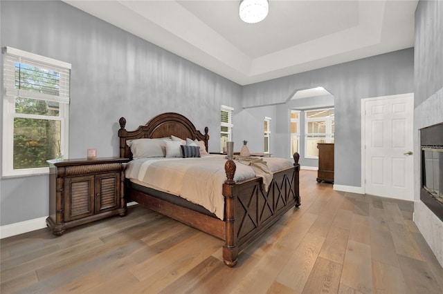 bedroom with light wood-type flooring and a tray ceiling