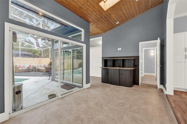 interior space featuring high vaulted ceiling, a skylight, and wooden ceiling