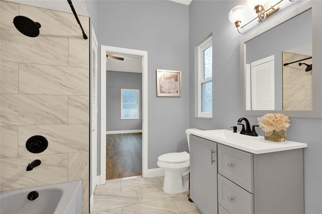 full bathroom featuring tiled shower / bath, vanity, and toilet