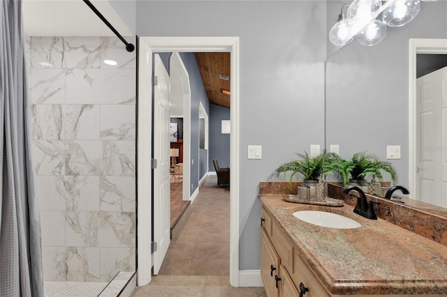 bathroom with tiled shower, vanity, and tile patterned flooring