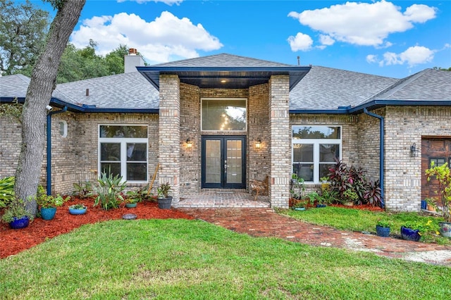 entrance to property with french doors, brick siding, and a shingled roof