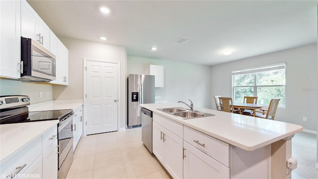 kitchen with white cabinets, appliances with stainless steel finishes, an island with sink, and sink