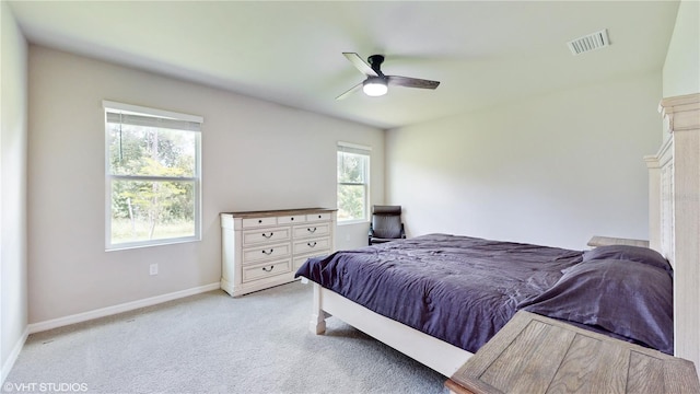 bedroom with multiple windows, light colored carpet, and ceiling fan