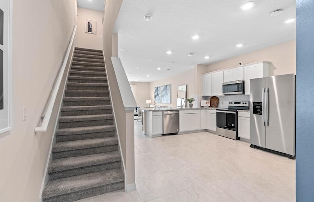 kitchen featuring light tile patterned floors, white cabinetry, kitchen peninsula, and stainless steel appliances