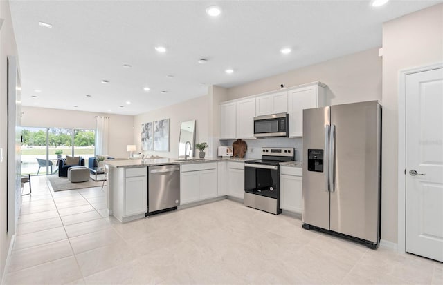 kitchen featuring appliances with stainless steel finishes, kitchen peninsula, light tile patterned floors, and sink