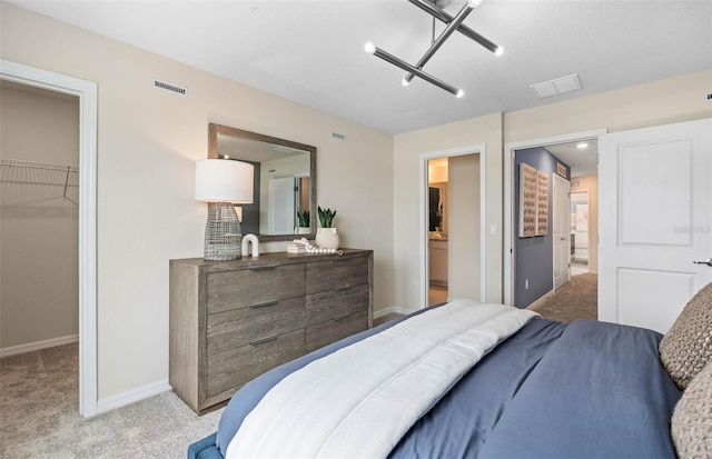 bedroom with light colored carpet, a walk in closet, and a closet