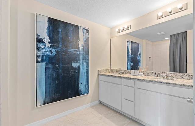 bathroom with double vanity, tile patterned flooring, and a textured ceiling