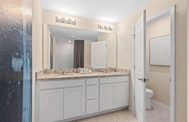 bathroom with a textured ceiling, toilet, dual bowl vanity, and tile patterned floors