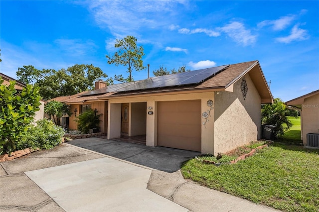 exterior space featuring a garage, a front yard, central AC, and solar panels