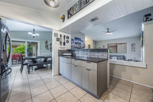 kitchen featuring a wealth of natural light, stainless steel fridge, light tile patterned floors, and ceiling fan with notable chandelier