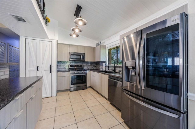 kitchen featuring light tile patterned floors, stainless steel appliances, sink, vaulted ceiling, and light brown cabinets