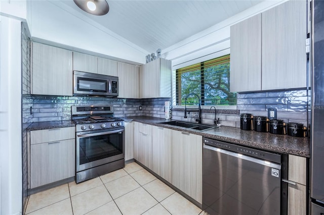 kitchen with vaulted ceiling, light tile patterned floors, backsplash, stainless steel appliances, and sink