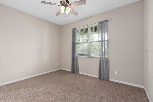 carpeted spare room featuring baseboards and a ceiling fan