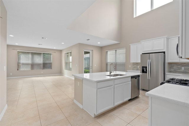 kitchen featuring a center island with sink, decorative backsplash, appliances with stainless steel finishes, open floor plan, and a sink