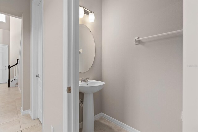 half bathroom featuring baseboards, a sink, and tile patterned floors