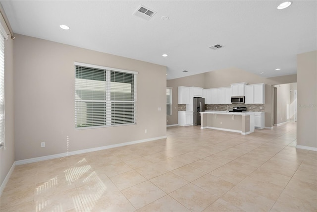 unfurnished living room with light tile patterned floors, vaulted ceiling, visible vents, and baseboards