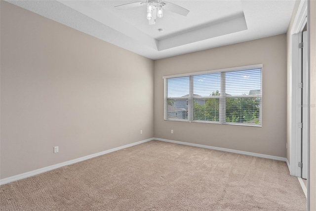 unfurnished room featuring baseboards, ceiling fan, a raised ceiling, and light colored carpet