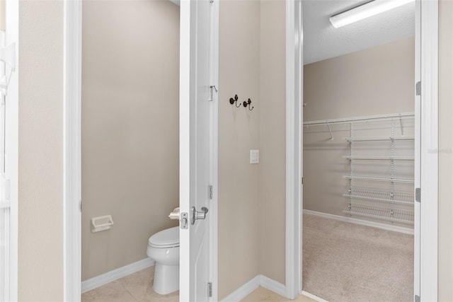 bathroom featuring toilet, baseboards, and tile patterned floors